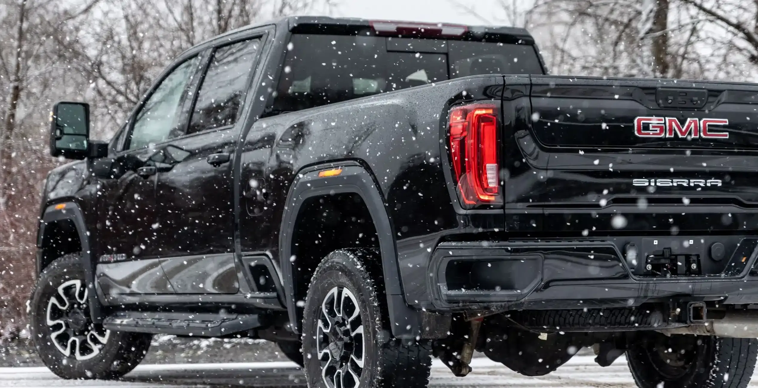 Duramax diesel repair in Palmer, AK at 1023 Diesel & Fleet: a black GMC Sierra truck seen from the rear on a snowy day, taillights glowing.