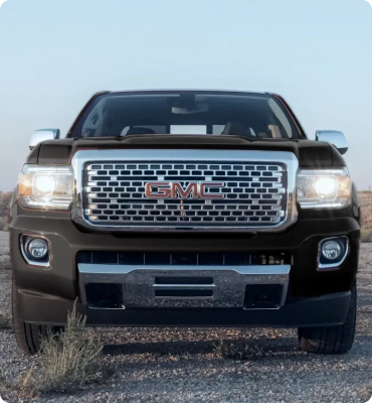 Front view of a black GMC truck parked on a gravel road