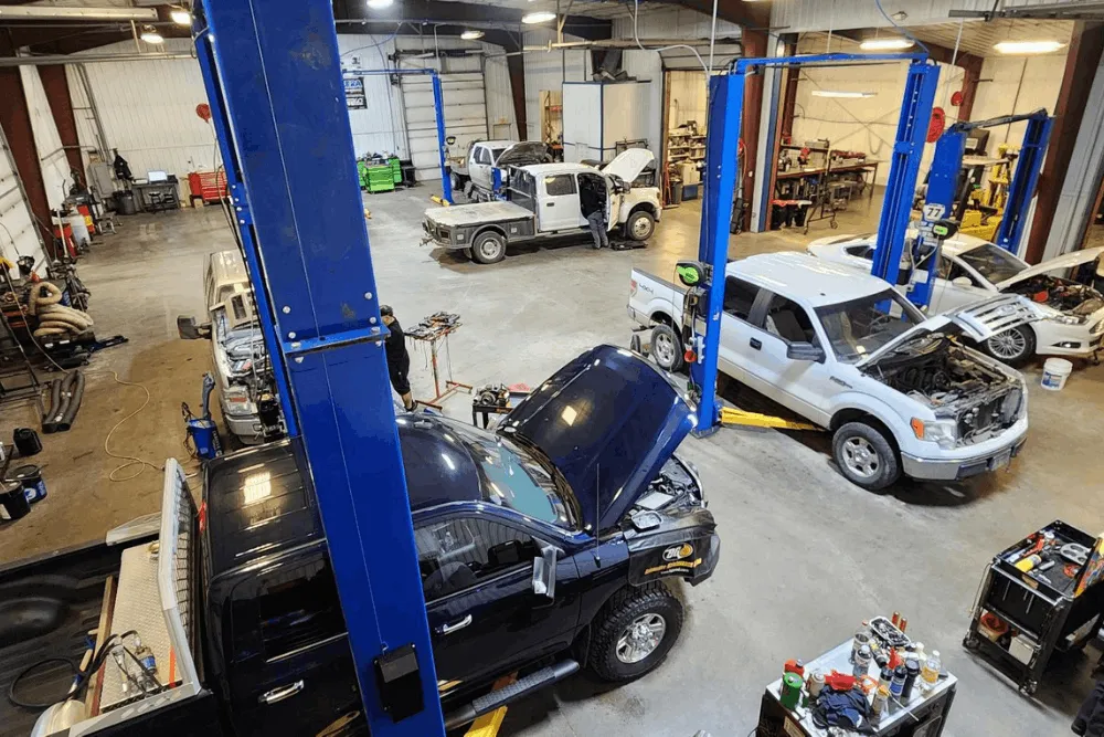 Diesel maintenance, diesel repair in Palmer, AK by 1023 Diesel & Fleet. Image of multiple diesel trucks and service vehicles being repaired inside a large shop with hydraulic lifts, highlighting comprehensive diesel diagnostics, fleet maintenance, and heavy-duty truck repair services.