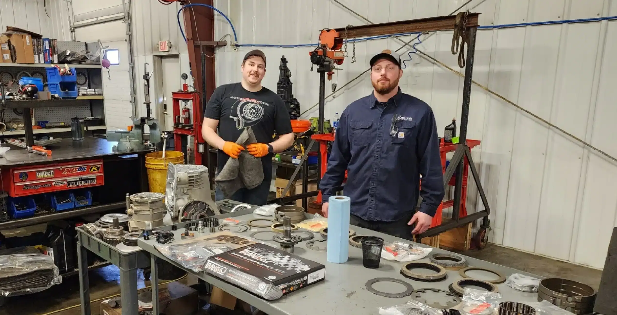 Two 1023 Diesel & Fleet technicians standing at a workbench covered with transmission parts in the shop.