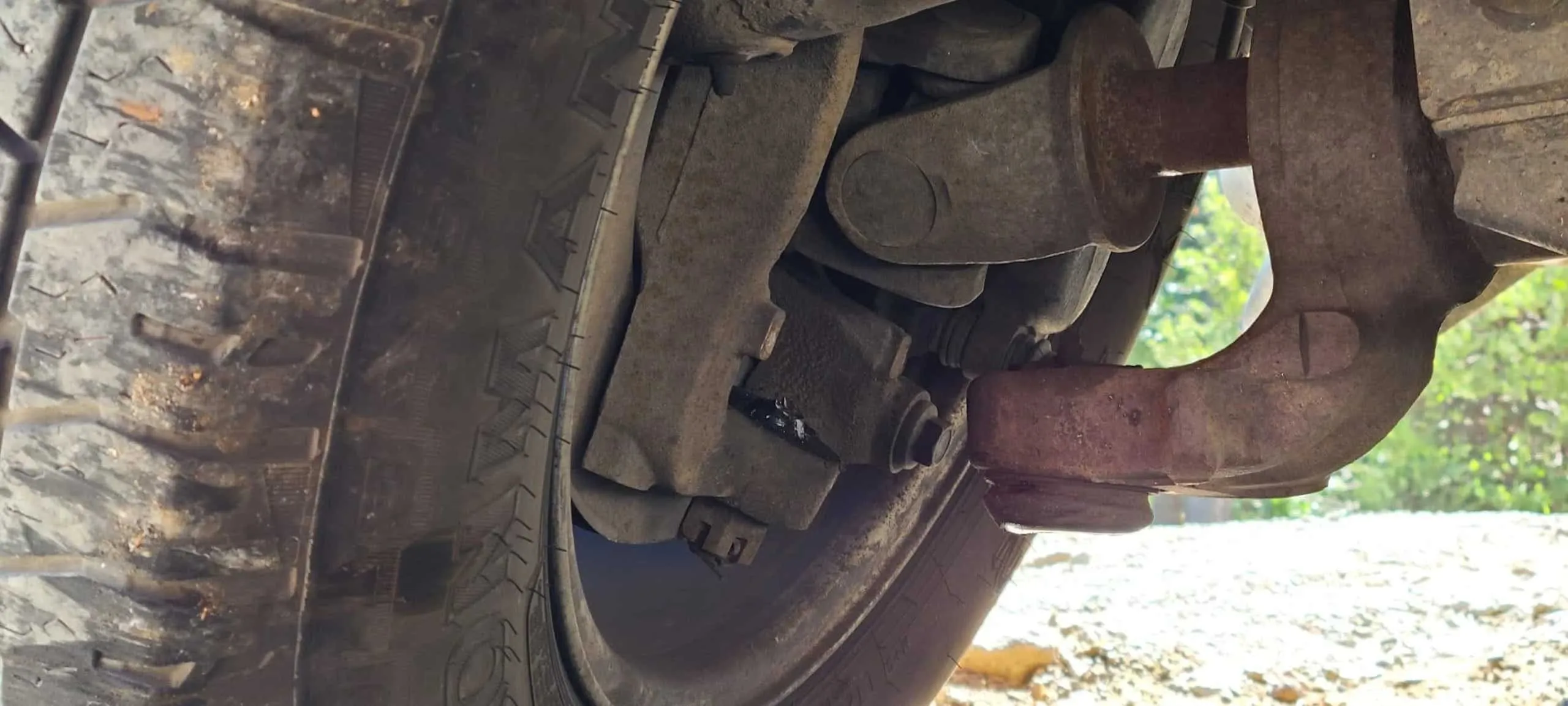Image of a close-up truck wheel assembly showing worn suspension components and undercarriage parts.